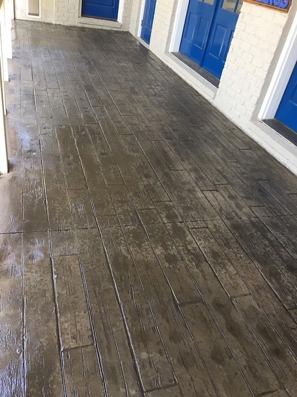Wet wooden walkway beside white building with blue doors and windows