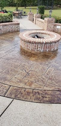 Brick fire pit on a stamped concrete patio in a landscaped park area