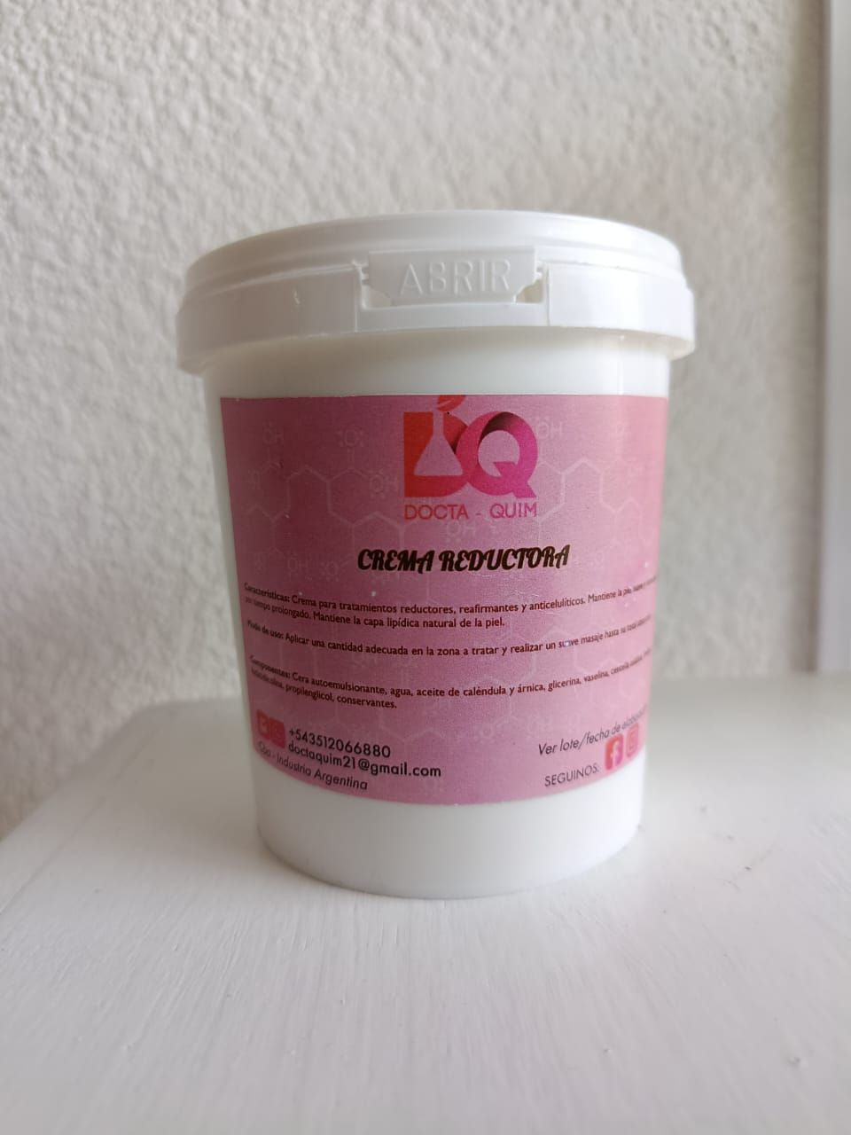 Envase blanco con etiqueta rosa, texto
