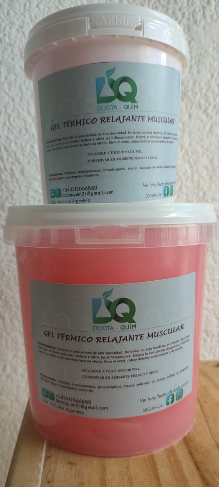 Dos recipientes rosas con etiquetas, apilados sobre una superficie de madera.