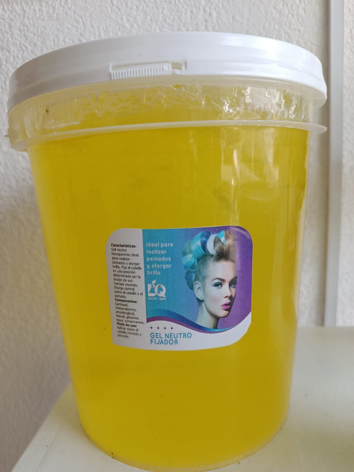 Gel fijador amarillo para el cabello en un envase de plástico con una etiqueta que muestra el cabello de una mujer con rulos.