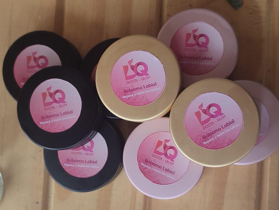 Montón de envases de cosméticos negros, dorados y rosas con etiquetas y texto rosas.