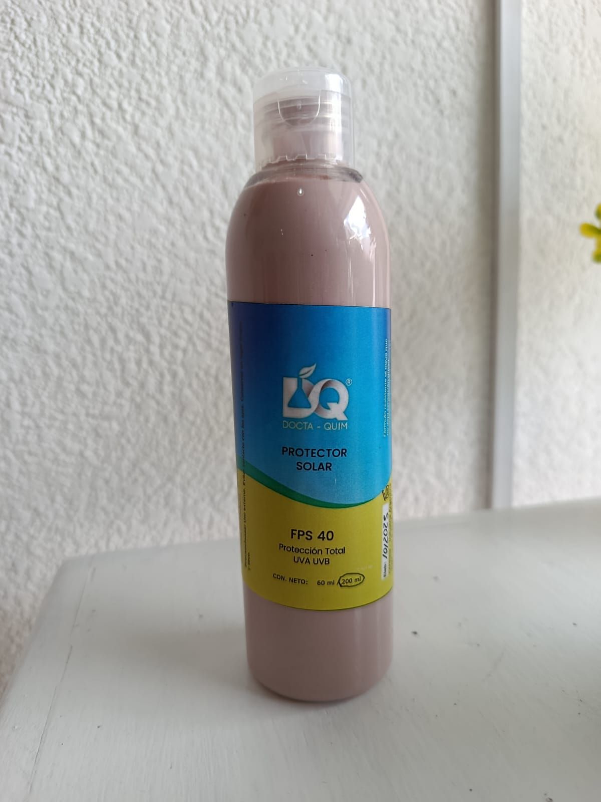 Botella blanca con etiqueta azul y amarilla que dice