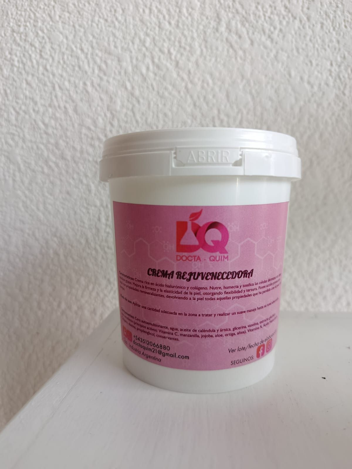 Envase blanco con etiqueta rosa, texto