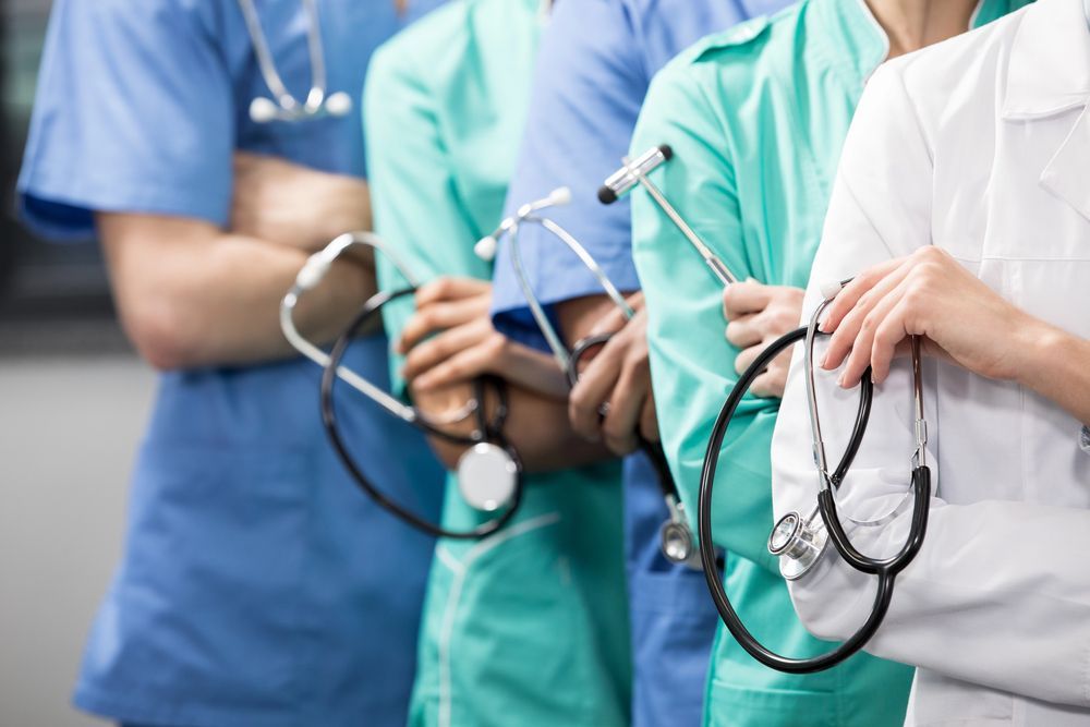 Profesionales sanitarios con uniformes médicos y estetoscopios, de pie en fila