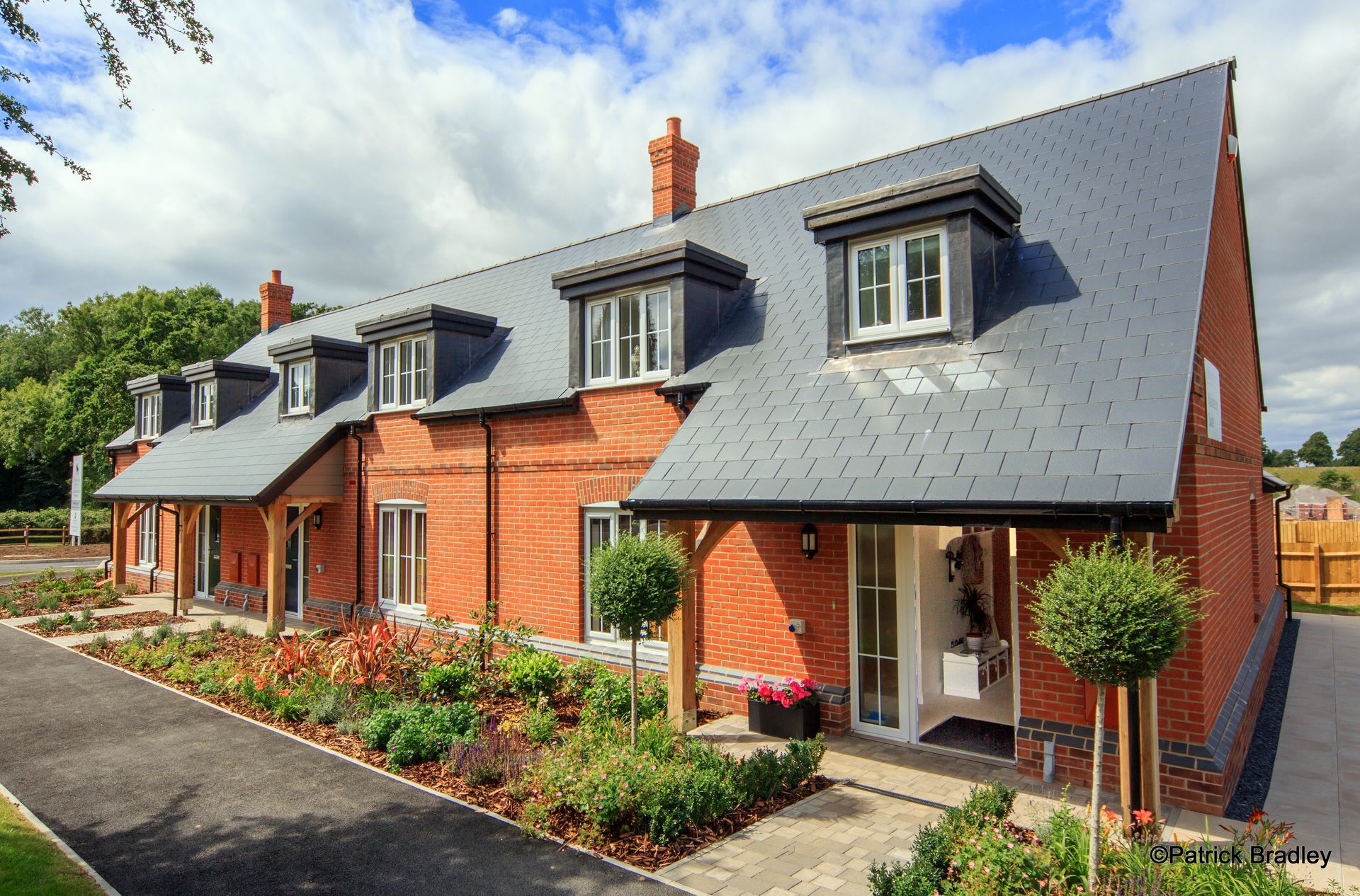 Limetree Village, A brick house with a slate roof and a driveway in front of it.