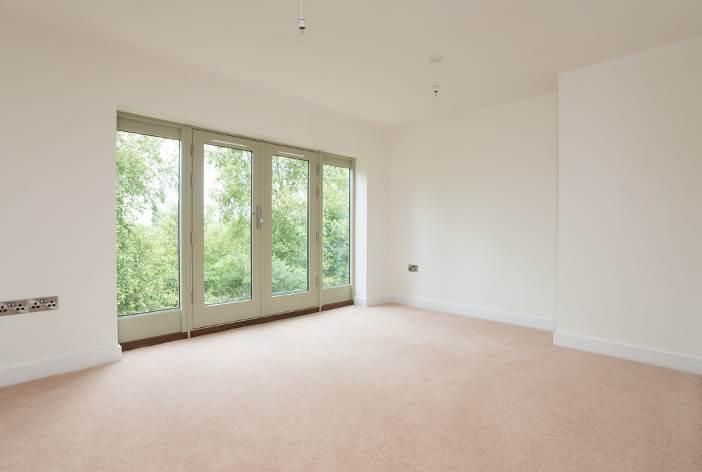 Brailes, An empty living room with a large window and sliding glass doors.