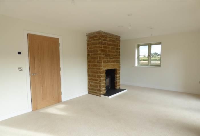Brailes, An empty living room with a brick fireplace and a wooden door