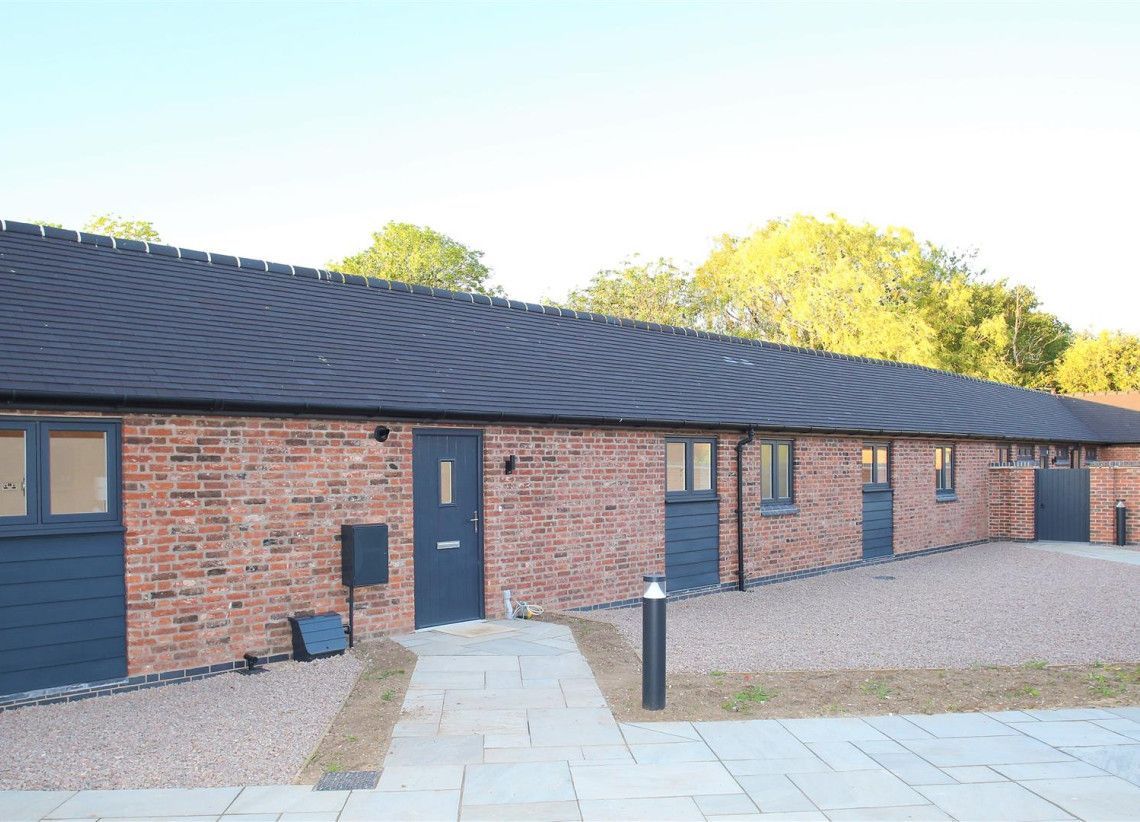 Newbold Farm, a brick house with a black roof and a walkway leading to it.