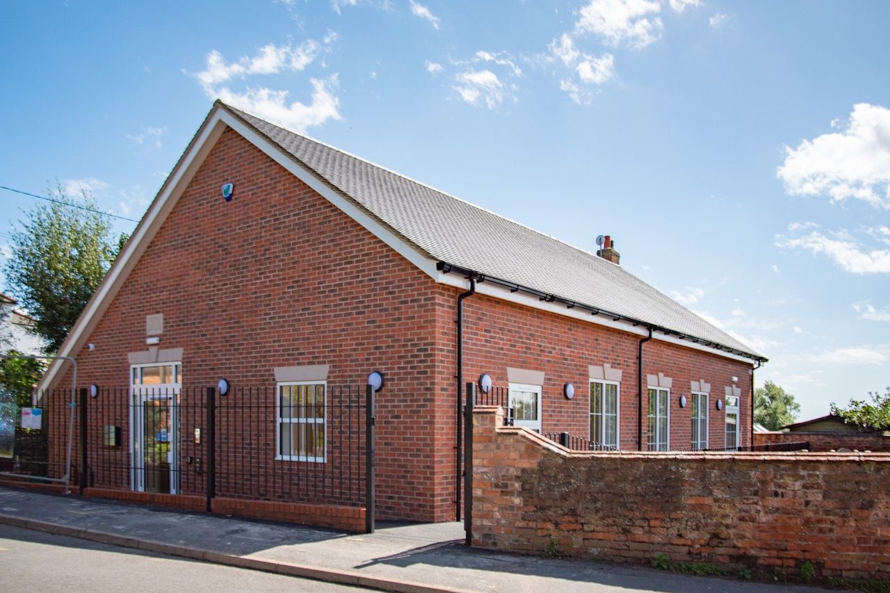 A large red brick building with a black roof and white windows.