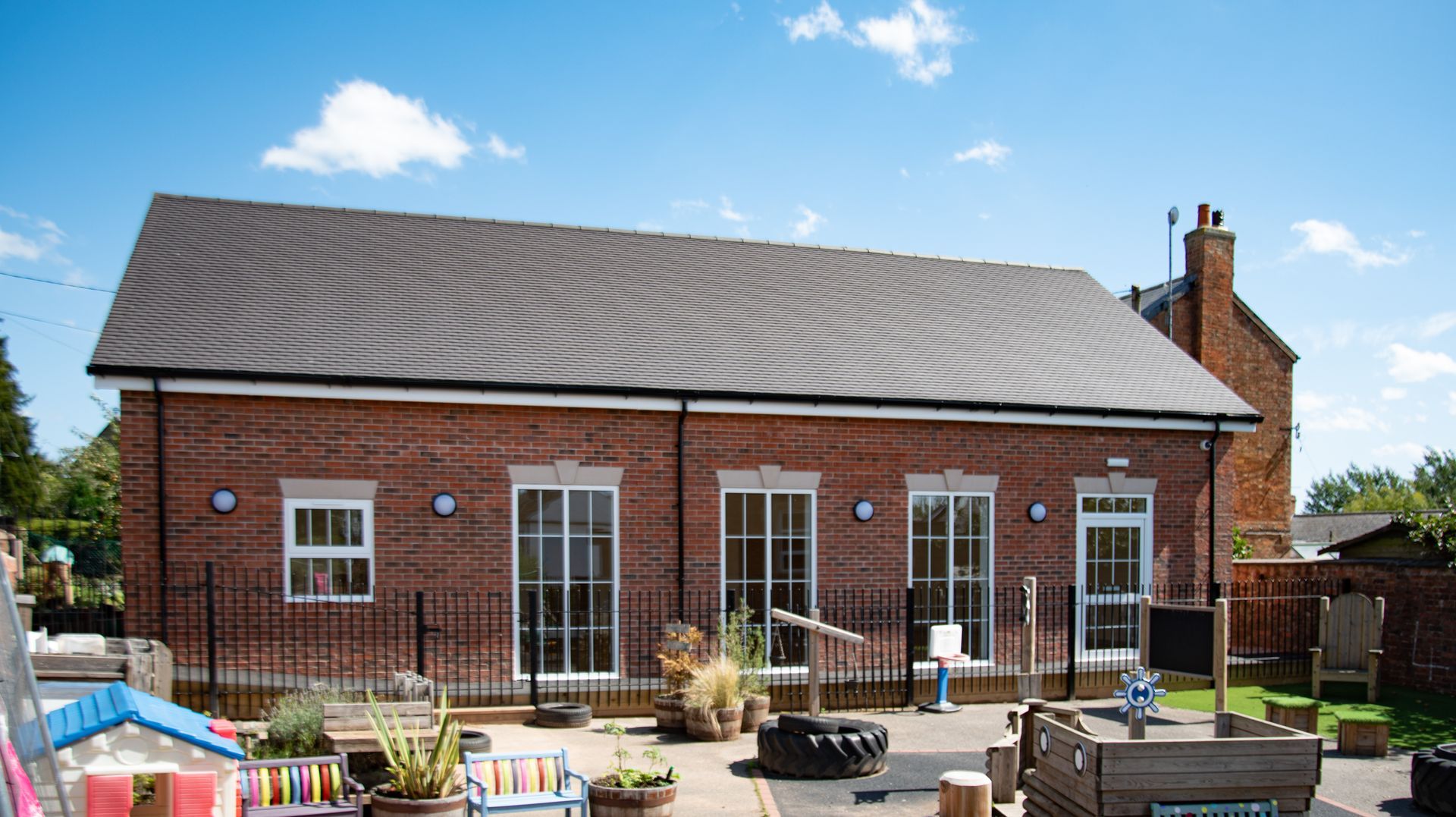 Old School Community Room, A large brick building with a lot of windows and a patio in front of it.