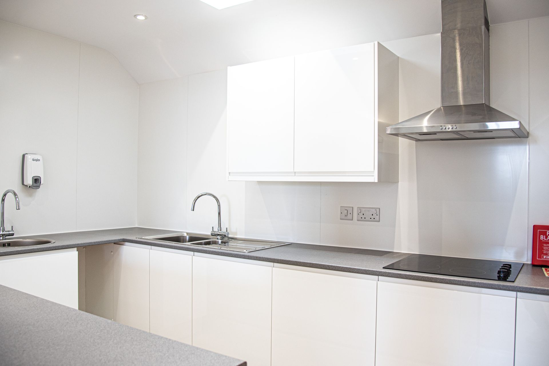 Old School Community Room, A kitchen with white cabinets and a stove top oven