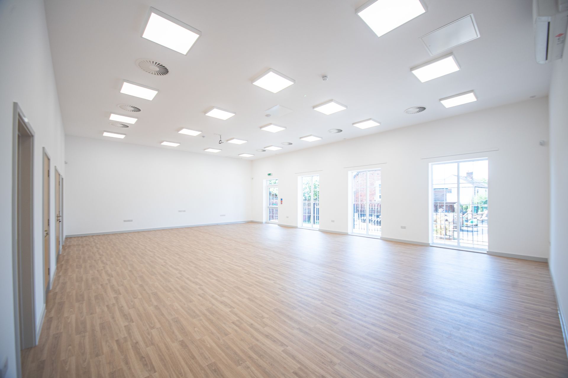 Old School Community Room, A large empty room with wooden floors and white walls.