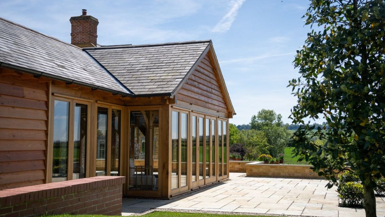 St Dennis Pool House, A large wooden house with a lot of windows and a slate roof