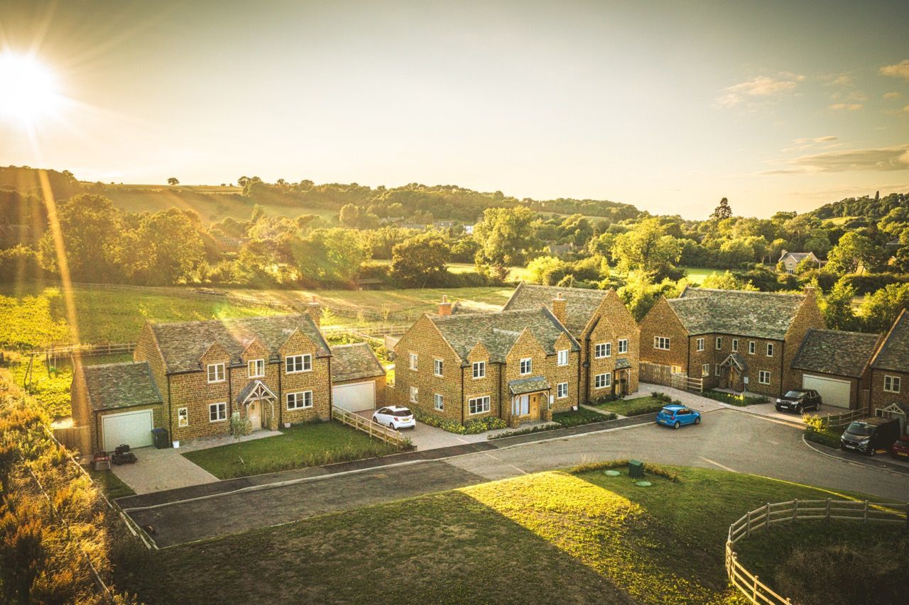 Brailes, An aerial view of a row of houses in a residential area with the sun shining through the trees.