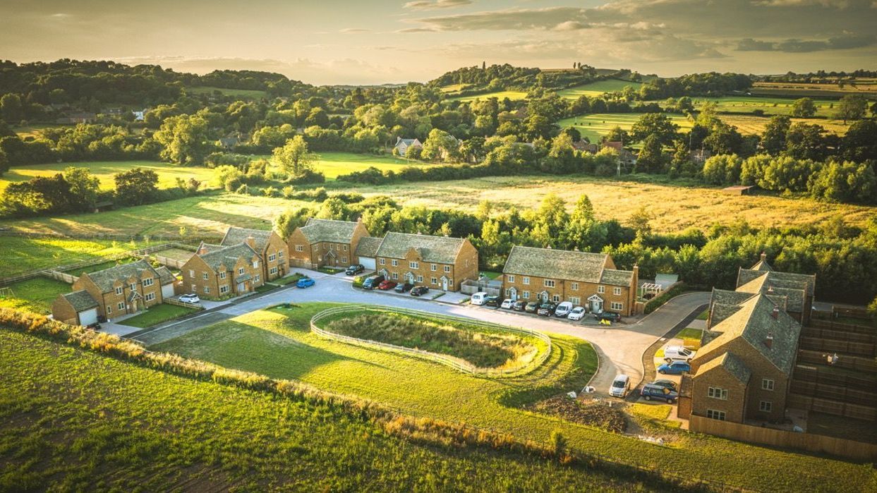 Warmington Fields, An aerial view of a residential area surrounded by fields and trees.
