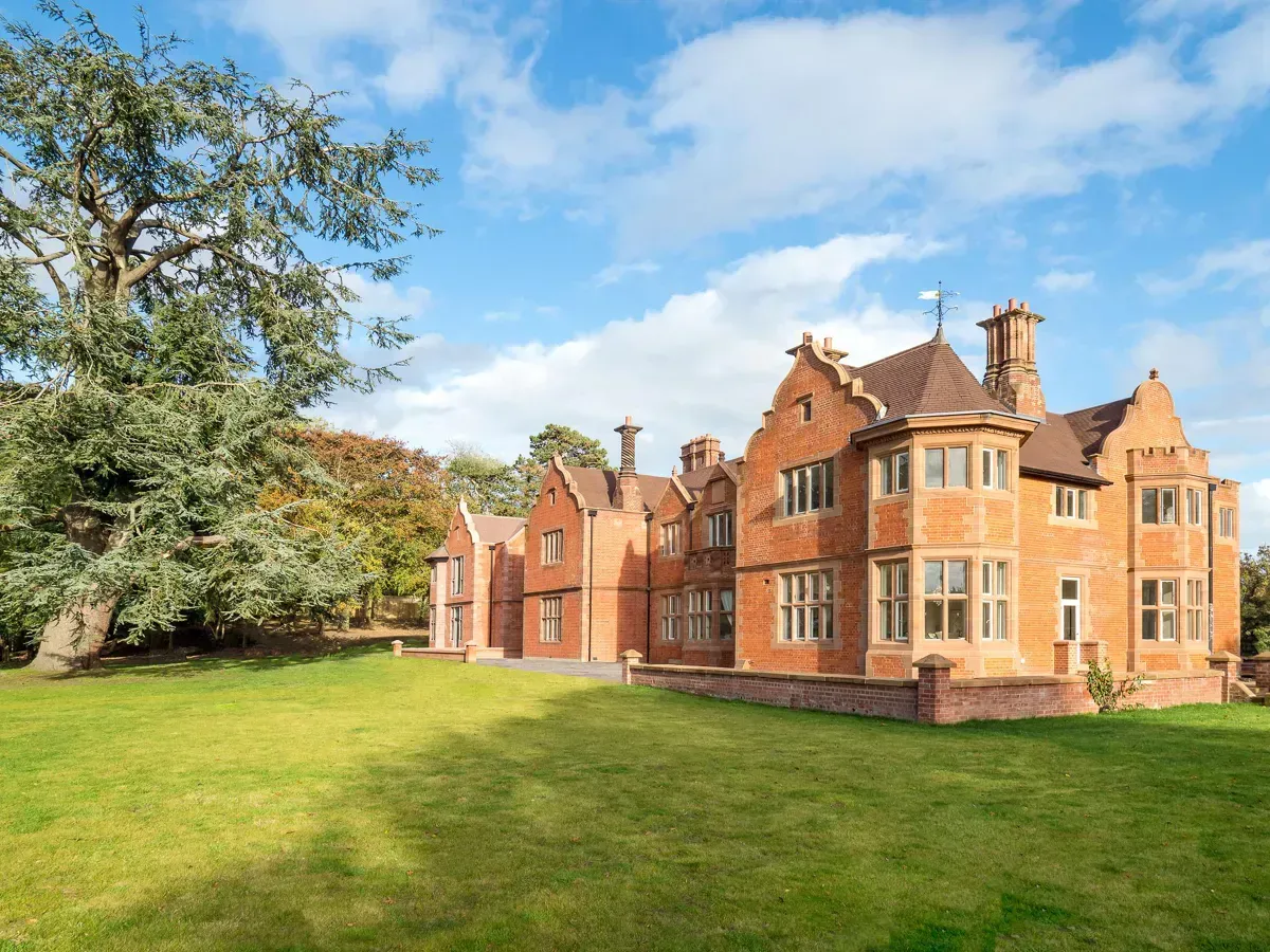 Milverton Hall, A large brick house is sitting on top of a lush green field.