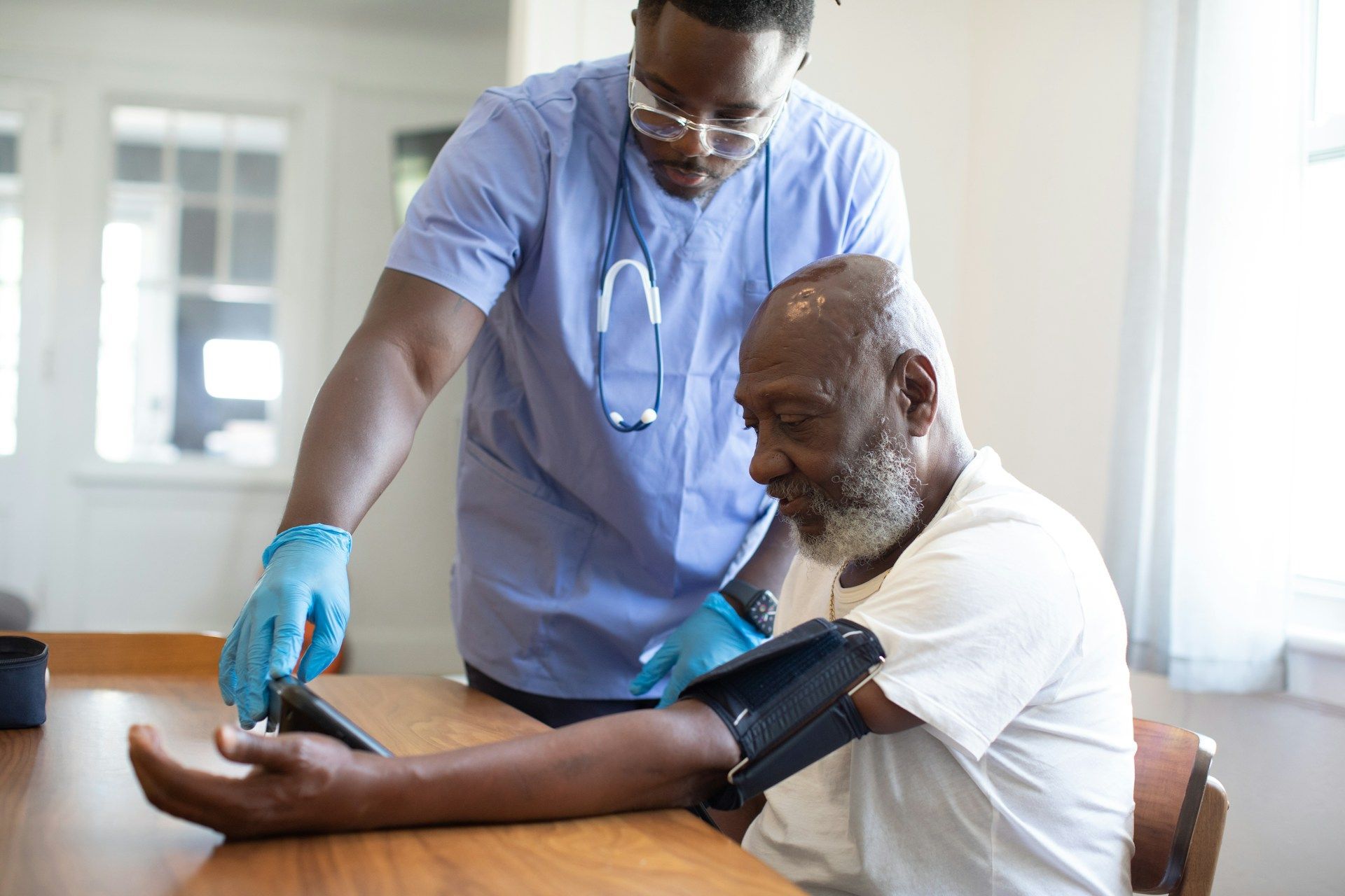 Healthcare worker checking blood pressure on a seated patient in a bright clinic room