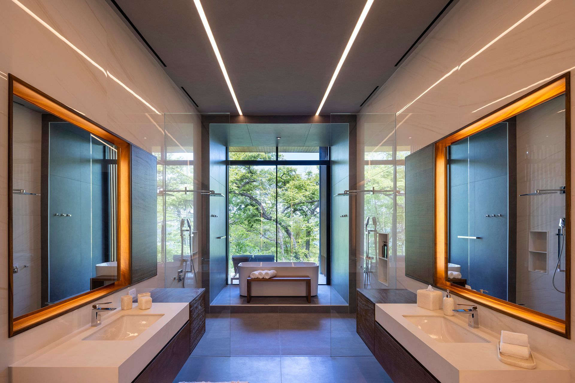 Luxury bathroom with two sinks, large mirrors, and a view of trees.
