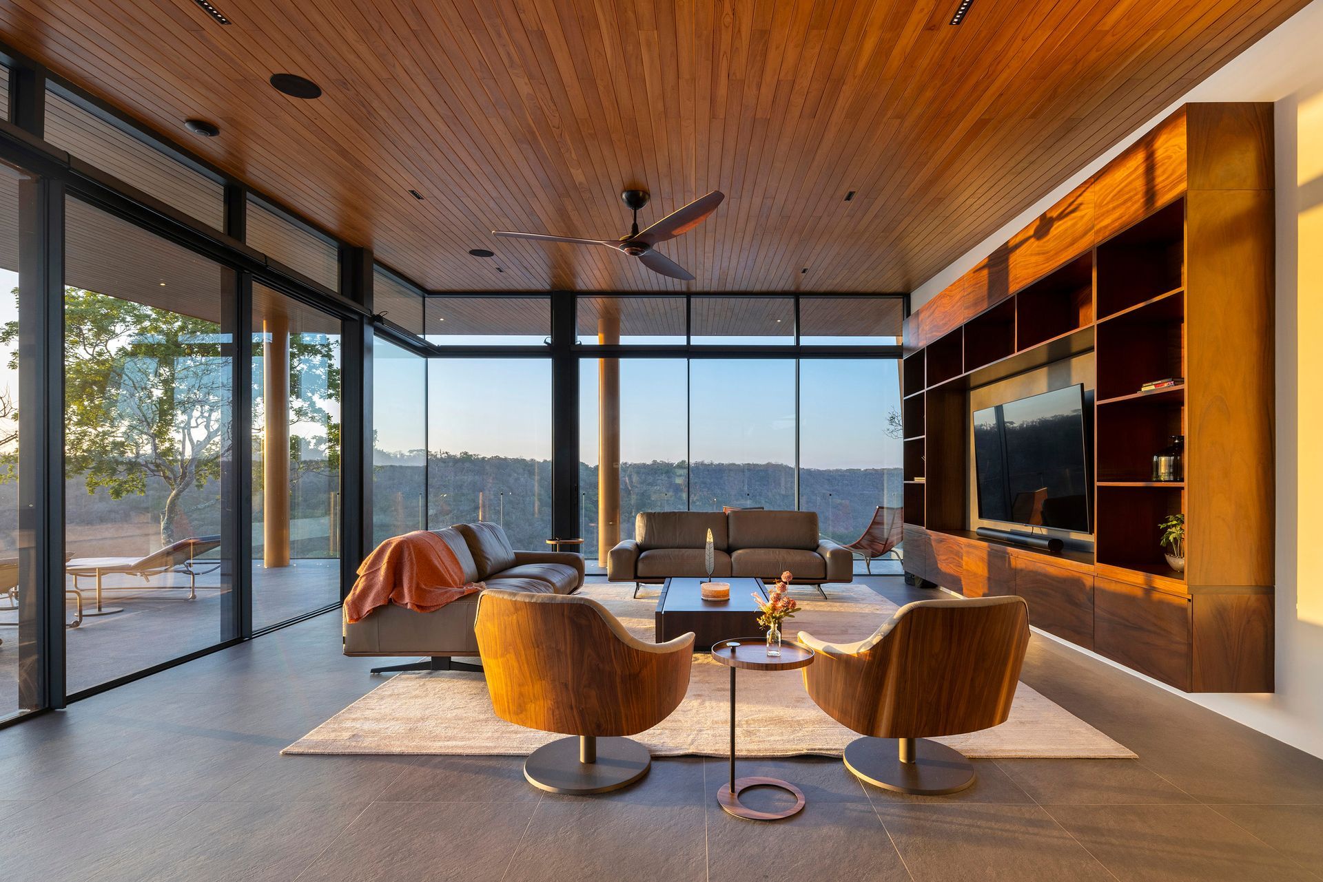 A living room with a lot of windows and a ceiling fan.