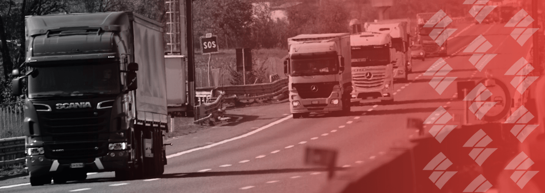 a black and white photo of a row of trucks driving down a highway .