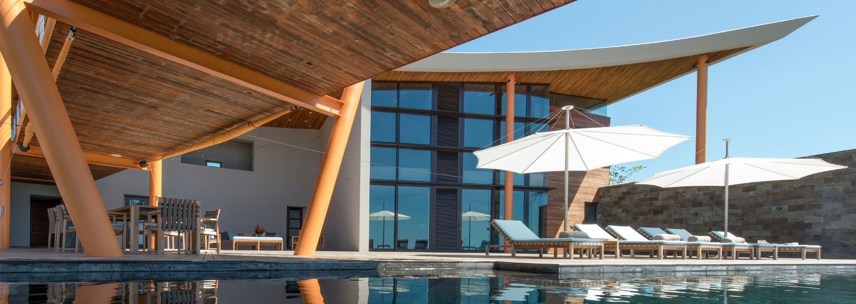 a large house with a pool and umbrellas in front of it