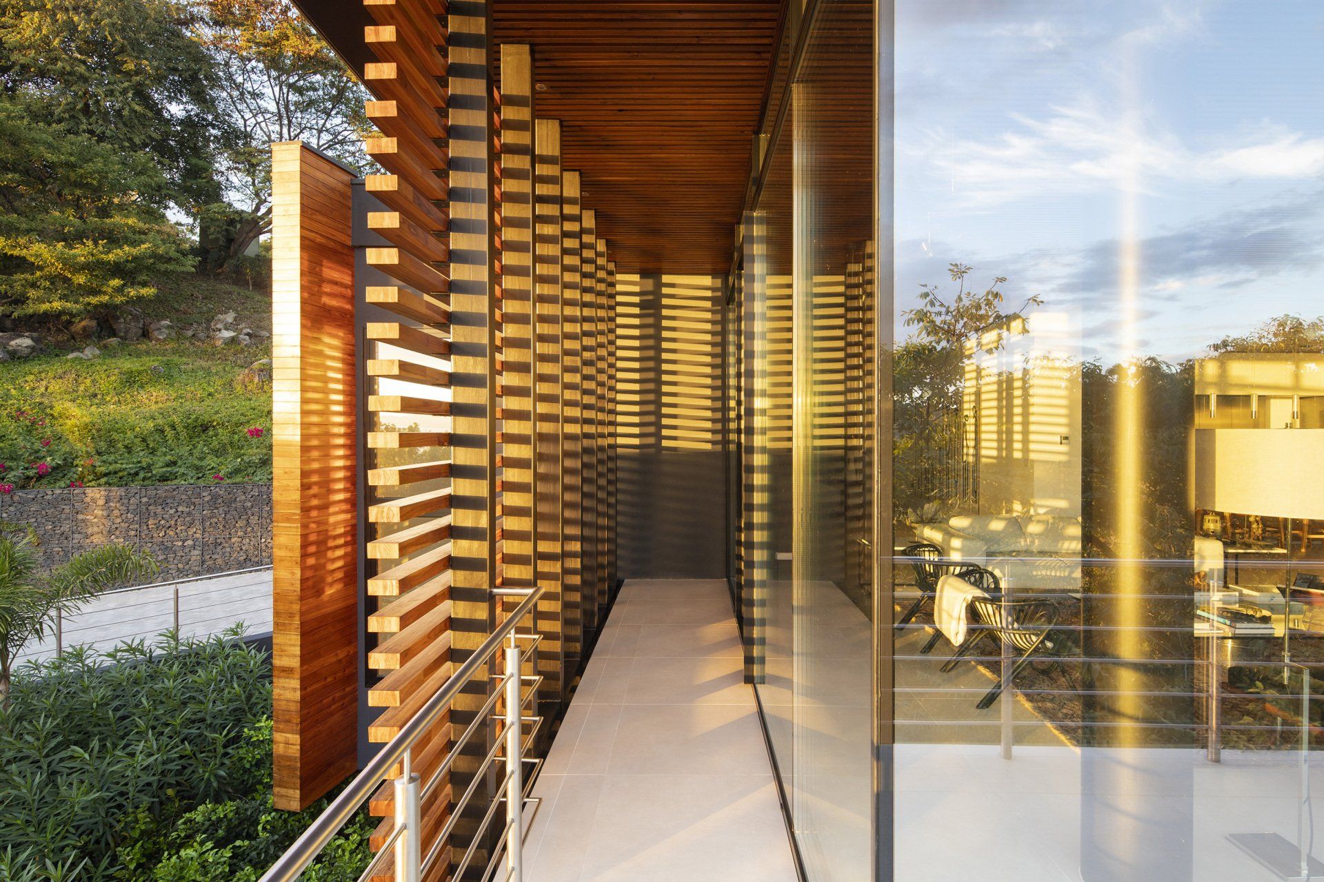 a walkway between two buildings with a wooden wall and a glass wall - casa aramara by sarco