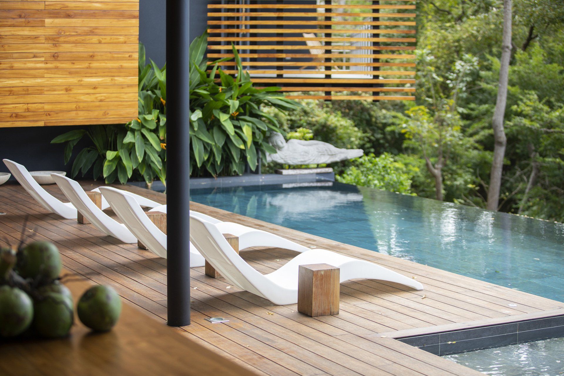 a row of lounge chairs are sitting on a wooden deck next to a swimming pool . - casa aramara by sarco