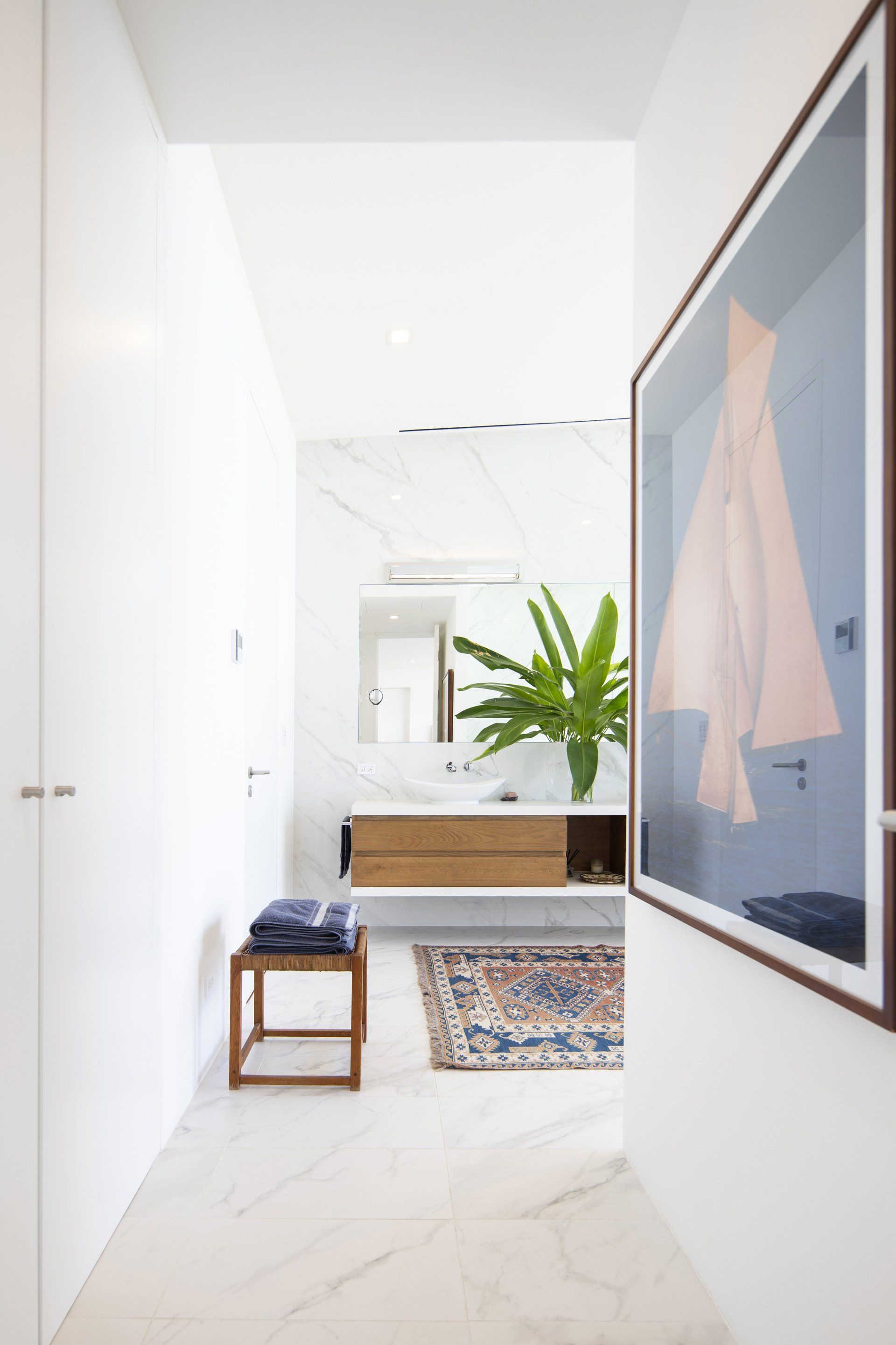 a hallway leading to a bathroom with a picture on the wall . - casa aramara by sarco