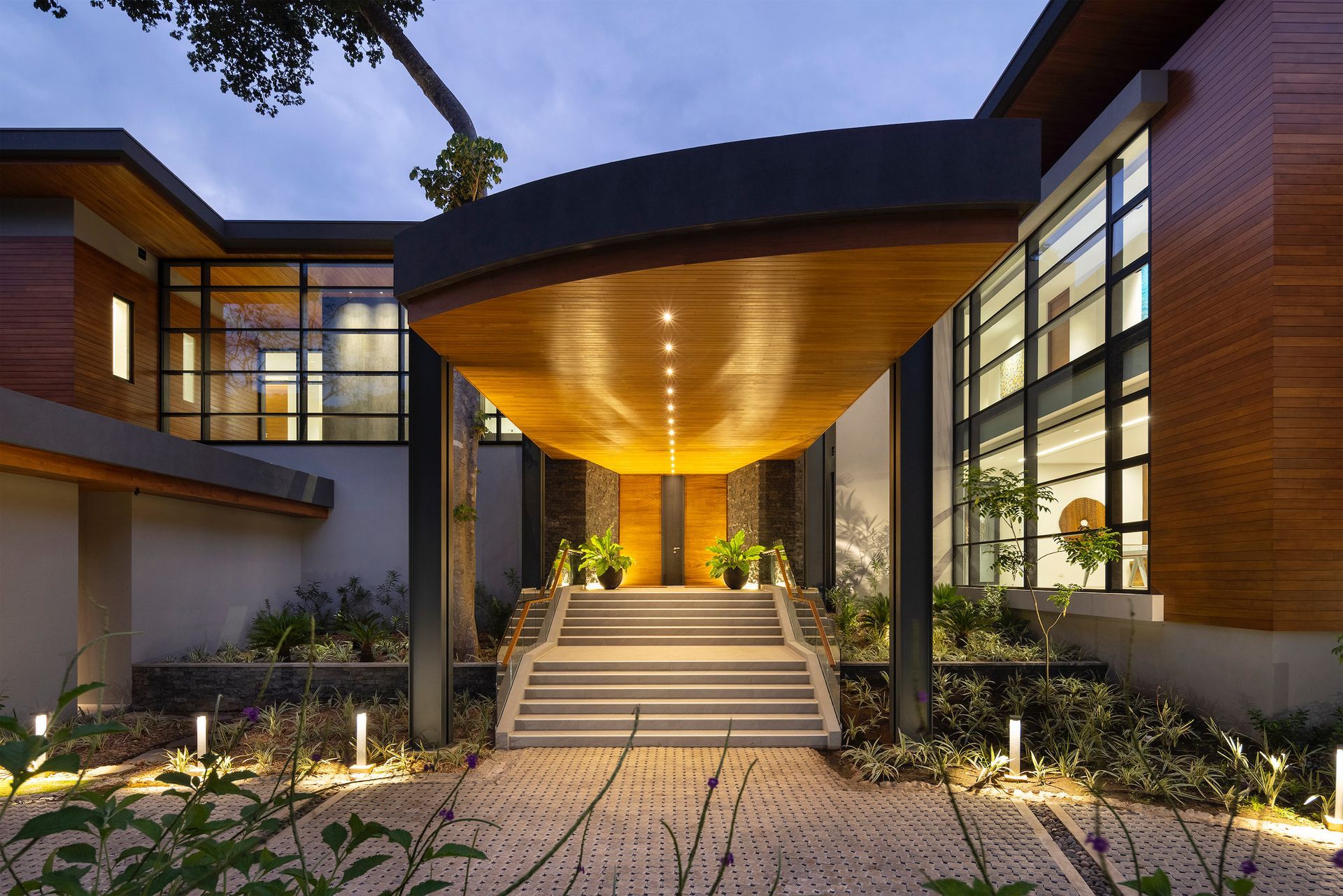Villa Avellana luxurious entrance with wooden facade, covered entrance, and illuminated pathway
