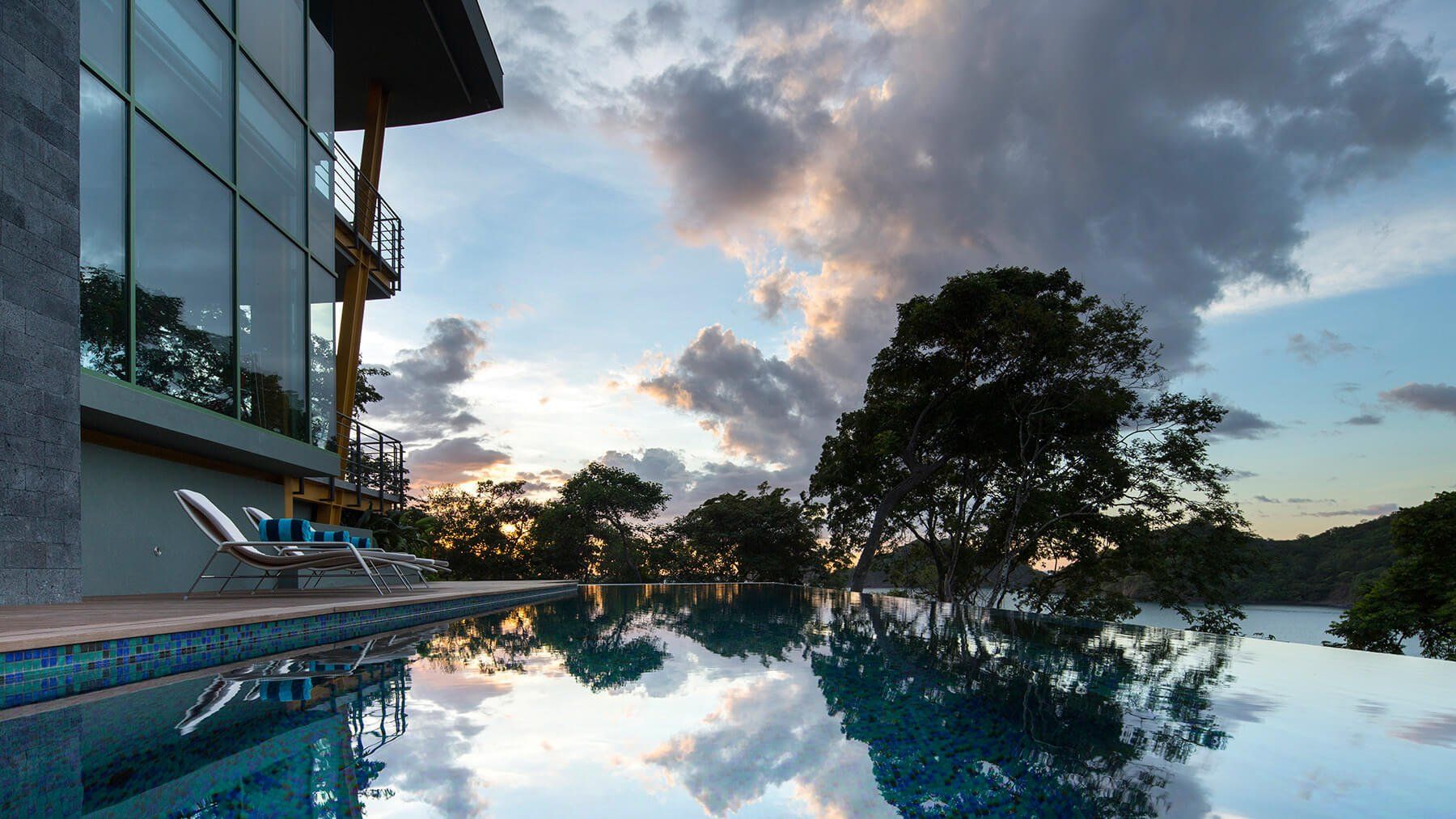 a large swimming pool is surrounded by trees and a building at sunset .