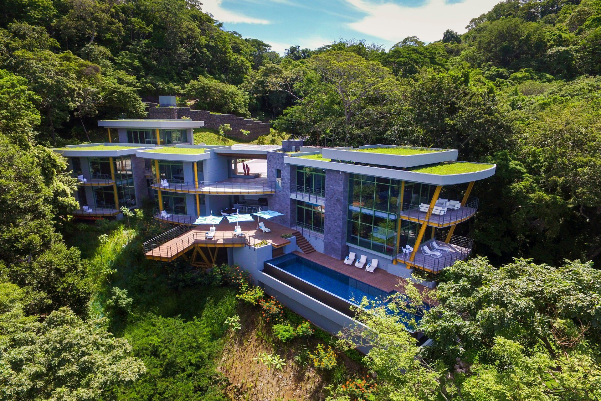 an aerial view of a large house with a swimming pool surrounded by trees .