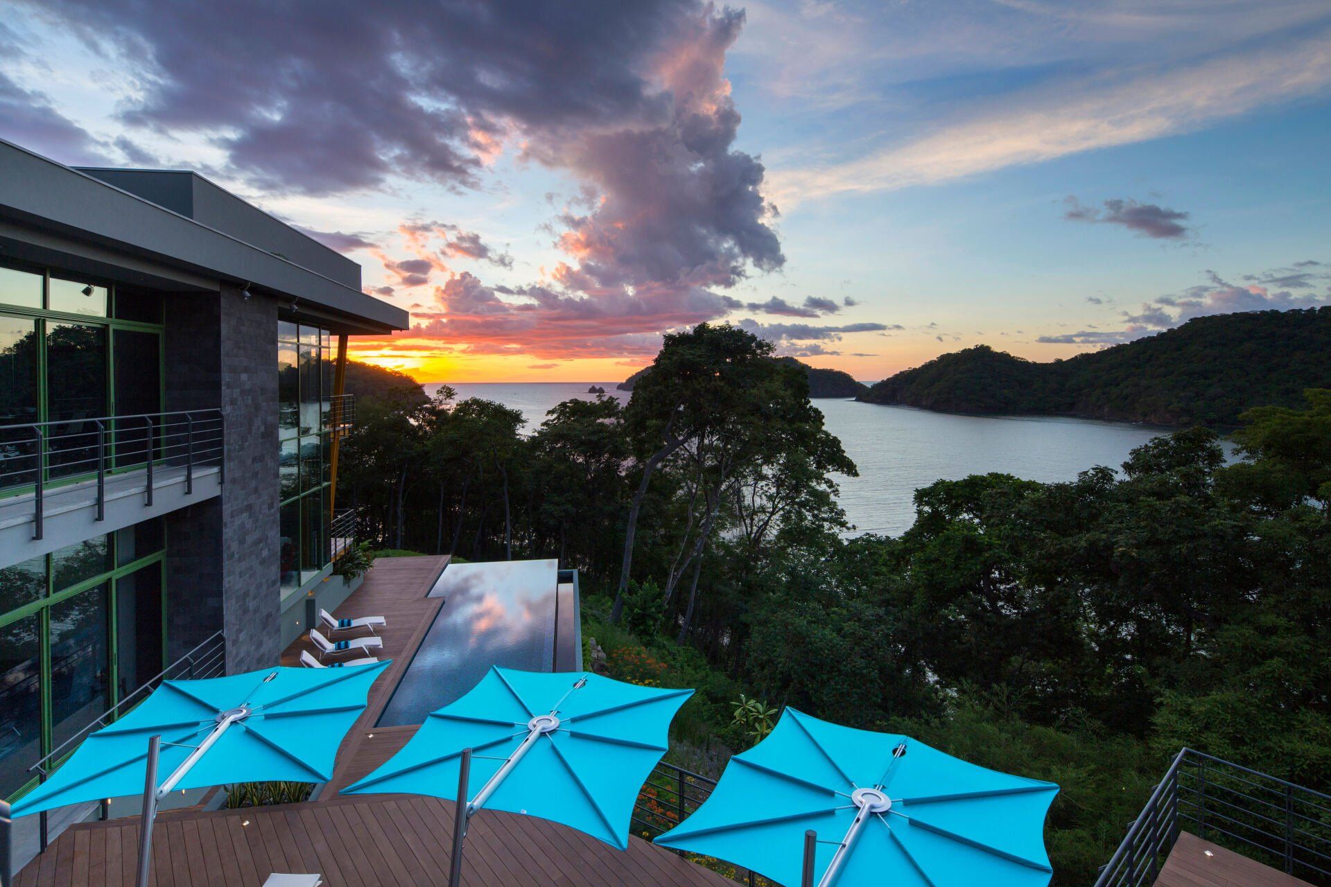 three blue umbrellas are sitting on a deck overlooking the ocean