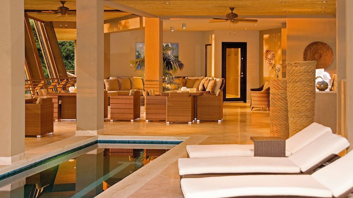 a large swimming pool surrounded by lounge chairs in a living room