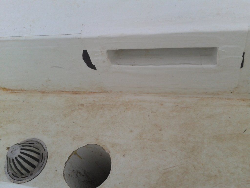a white wall with a drain and a hole in it