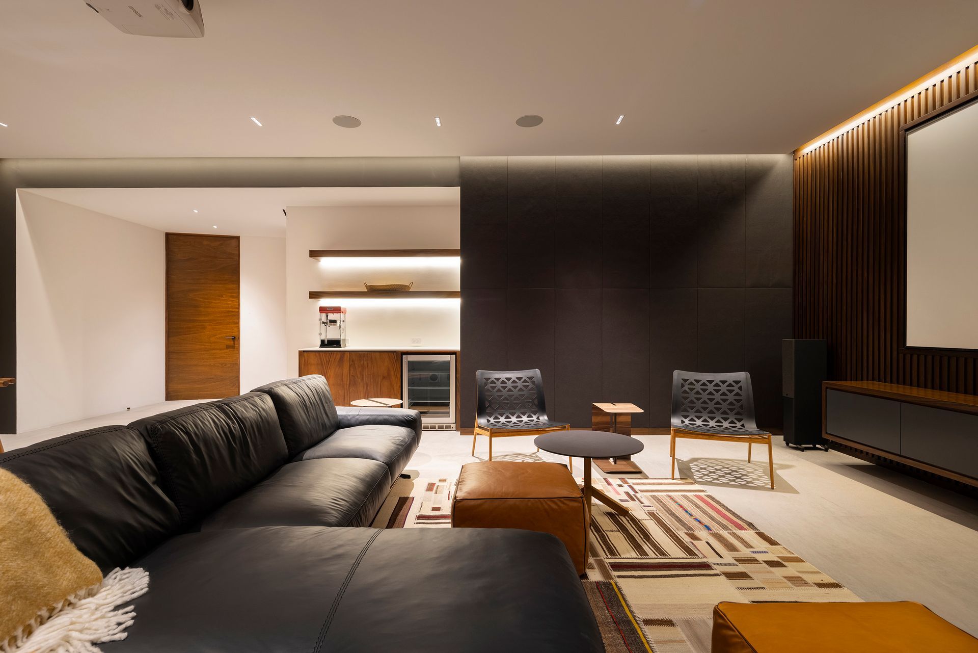 a living room with a couch and chairs and a projector screen