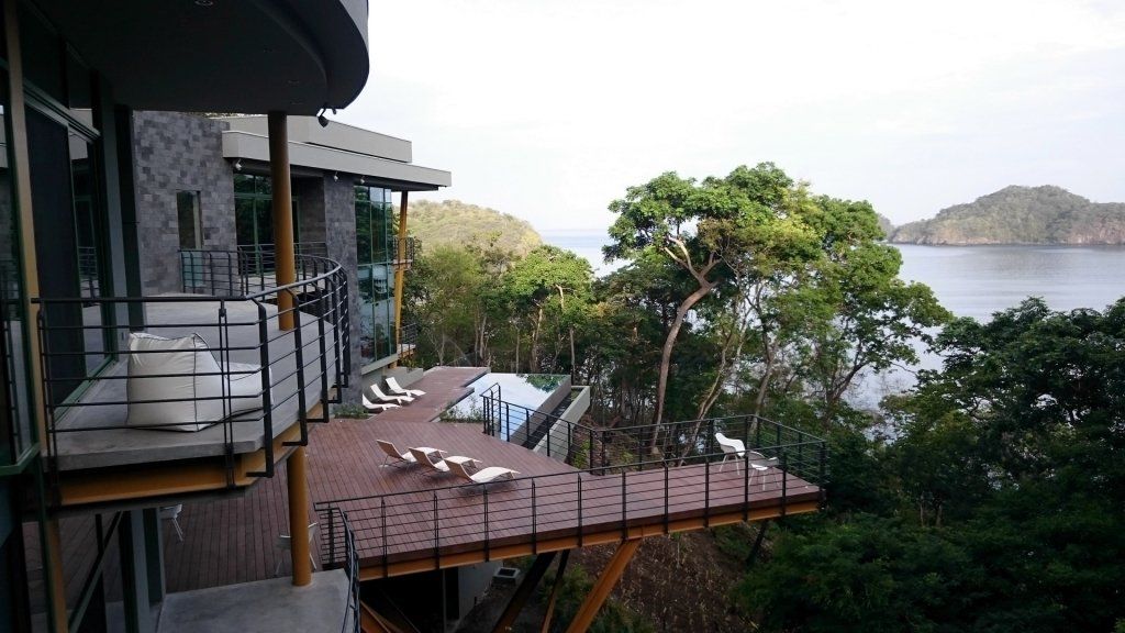 a large house with a wooden deck overlooking the ocean