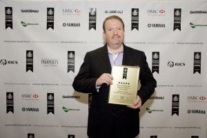 a man in a suit is holding a gold award