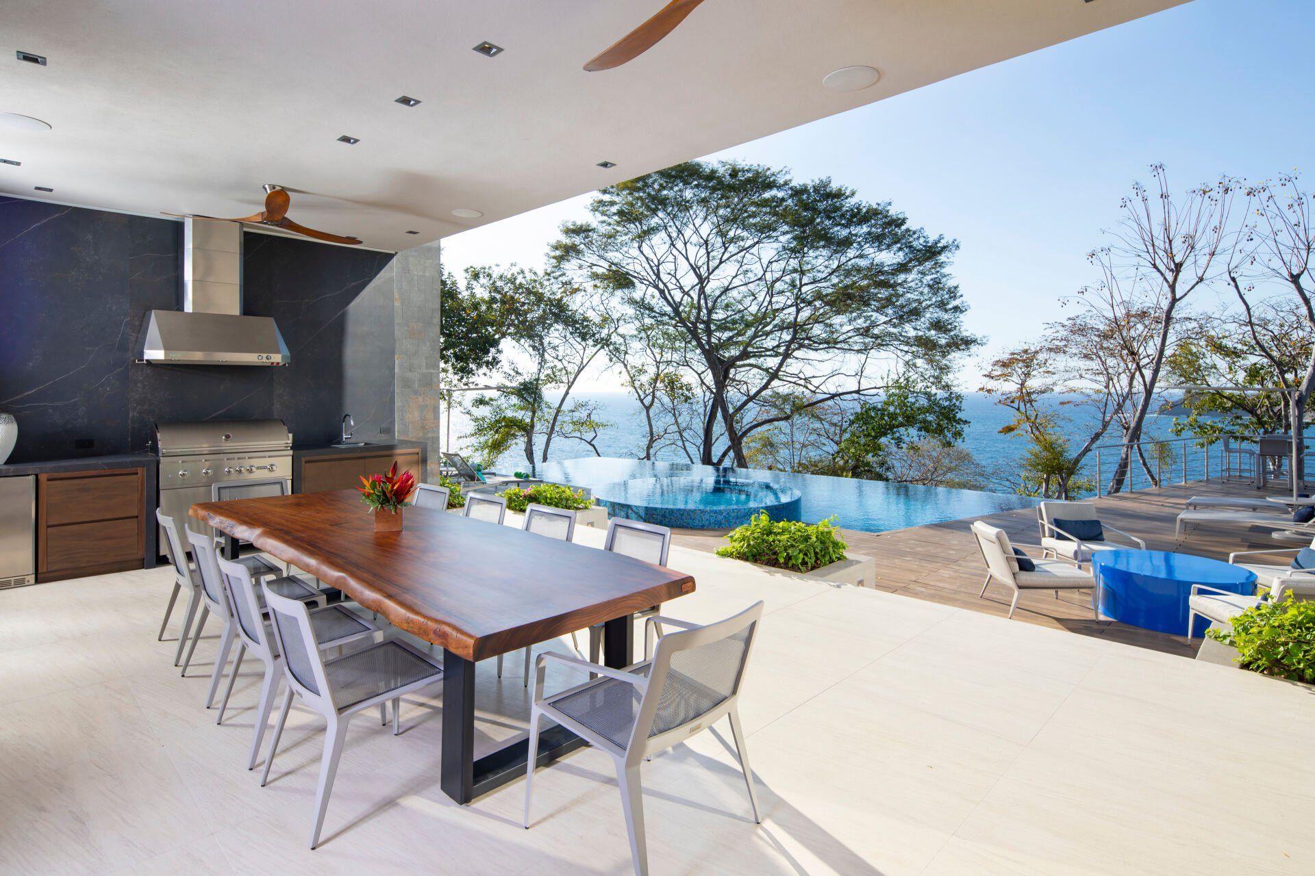 a large wooden table and chairs on a patio overlooking the ocean