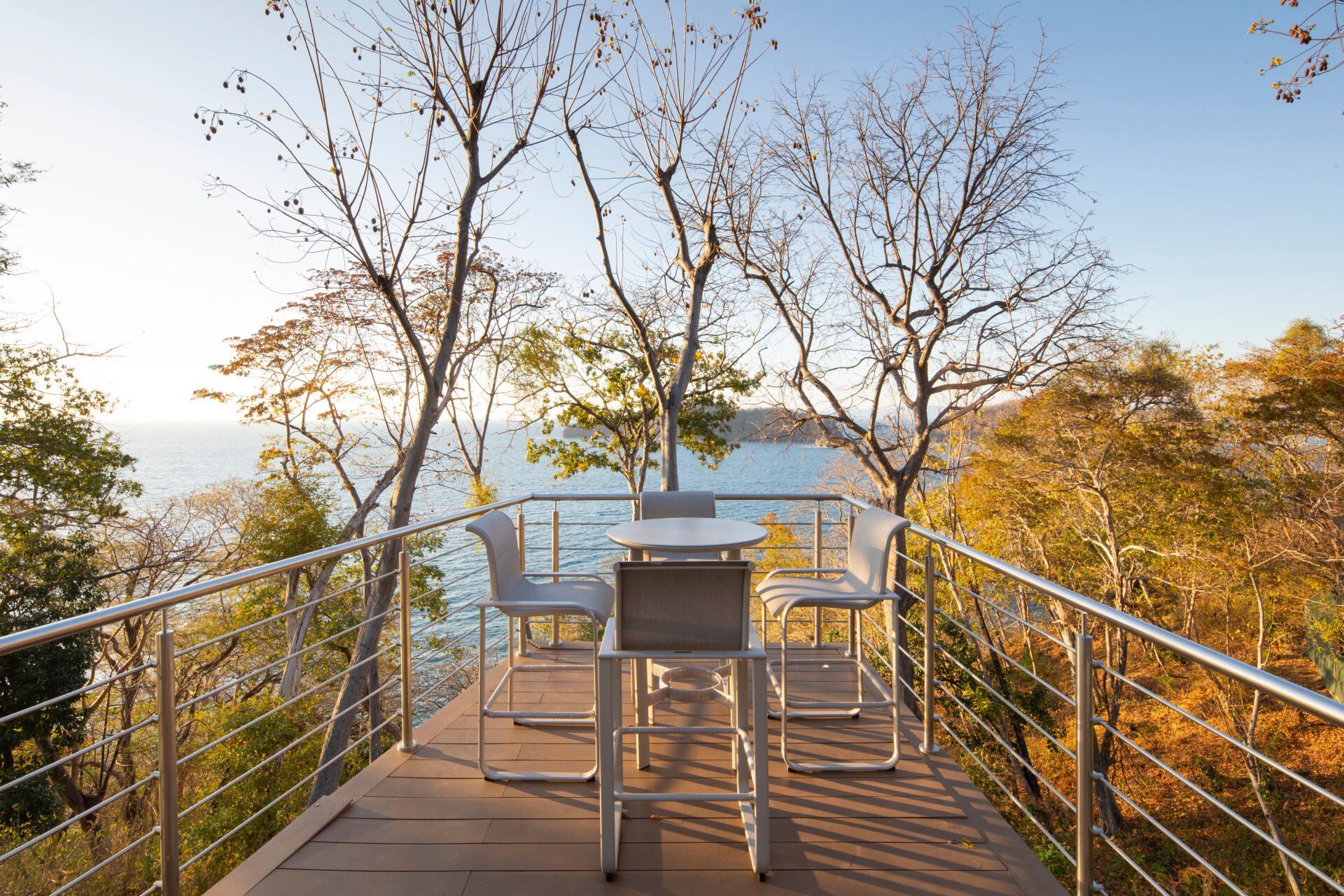 a table and chairs on a balcony overlooking the ocean .