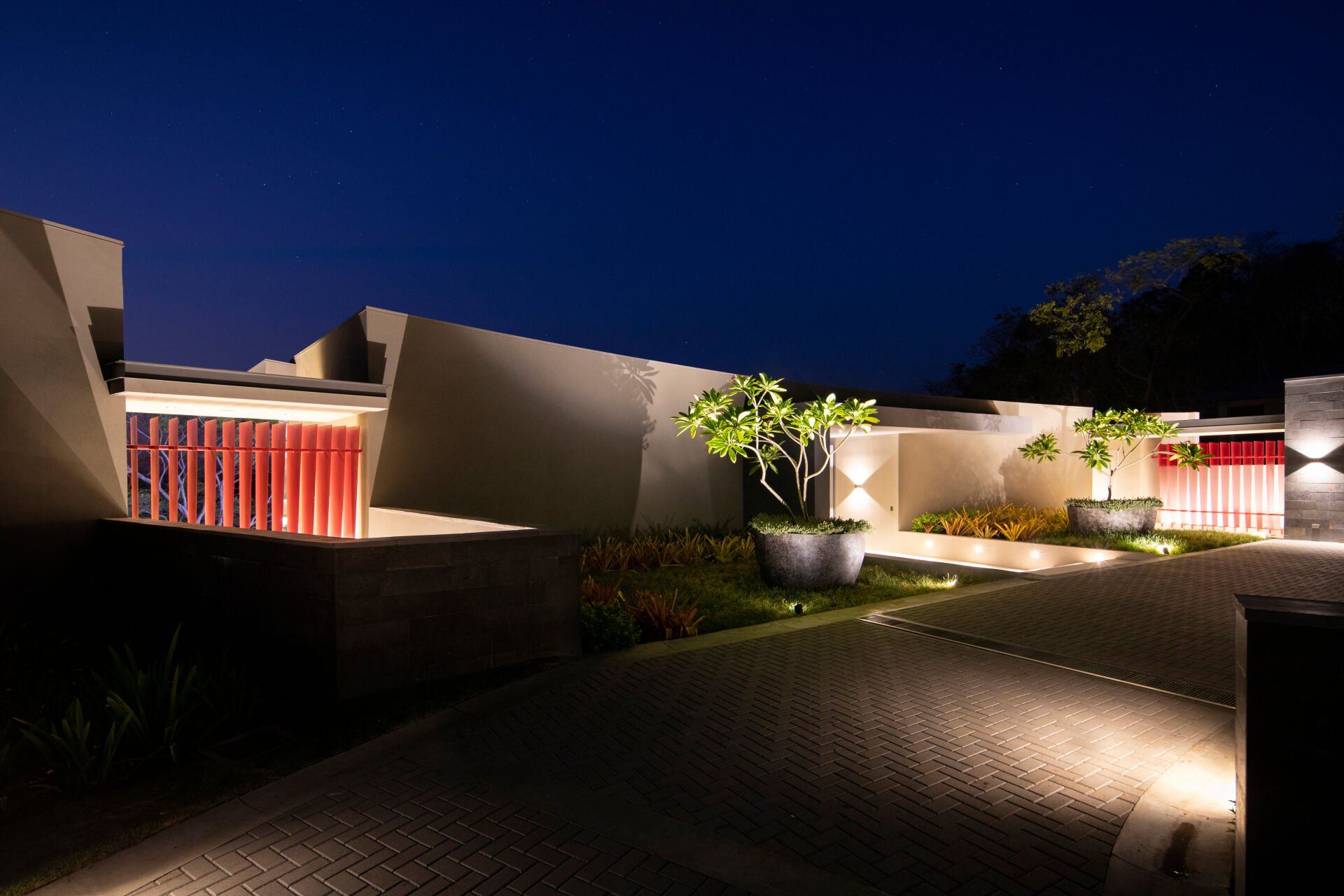 a house is lit up at night with a driveway leading to it