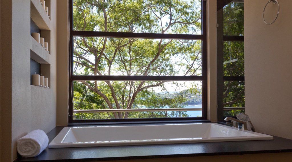 a bathtub in a bathroom next to a window with trees in the background