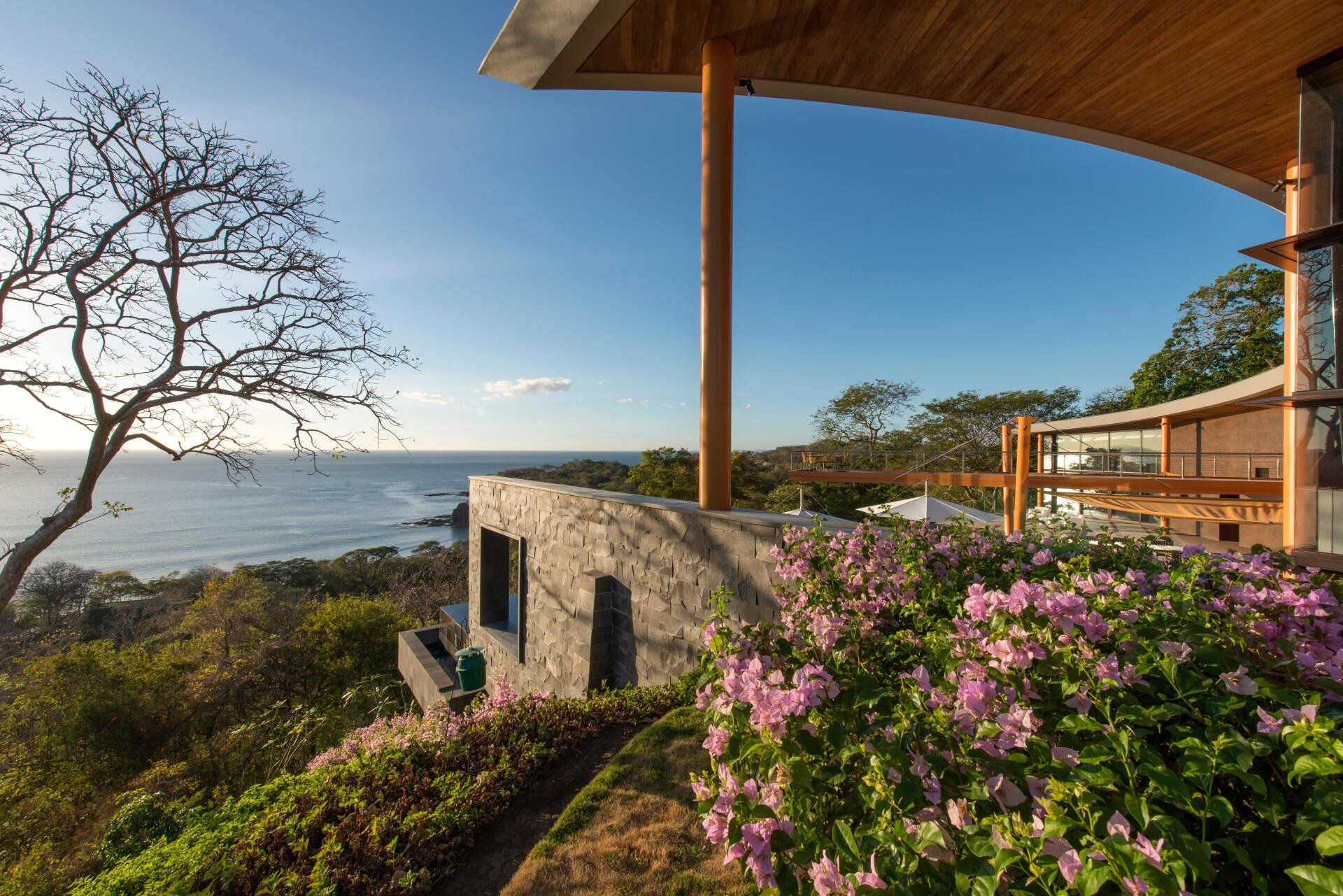 a house with a view of the ocean and flowers in front of it