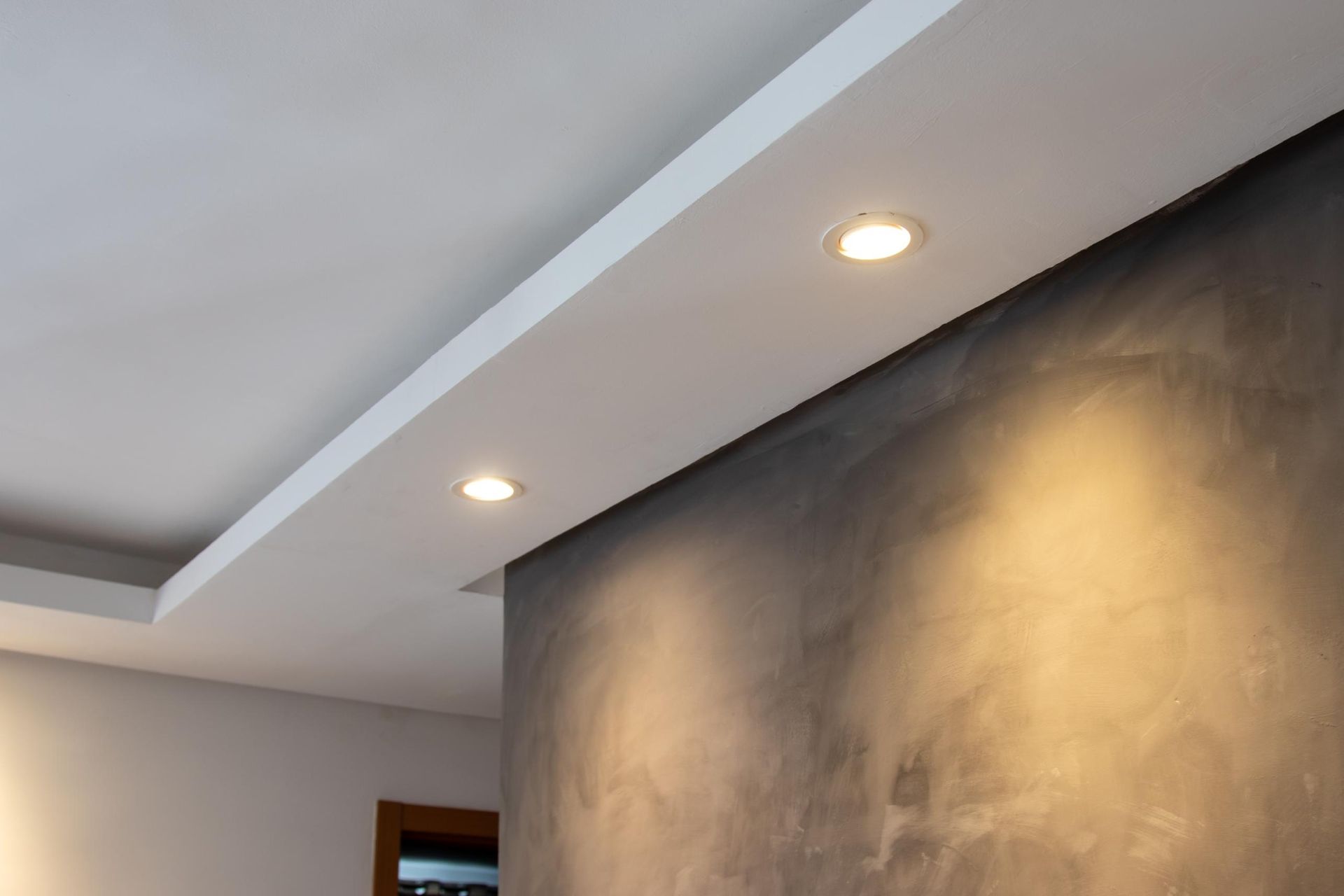 Modern interior with recessed ceiling lights and a large dark textured wall.