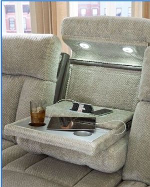 Airport lounge chair with a tray table holding a drink, laptop, and phone by a window