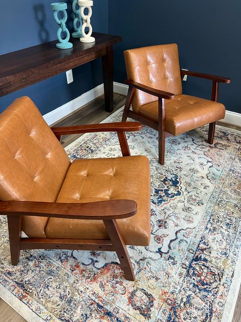 Two tan leather armchairs on a patterned rug in a modern living room.