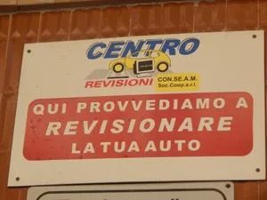 Sign for Centro Revisioni auto with red and white text on a brick wall