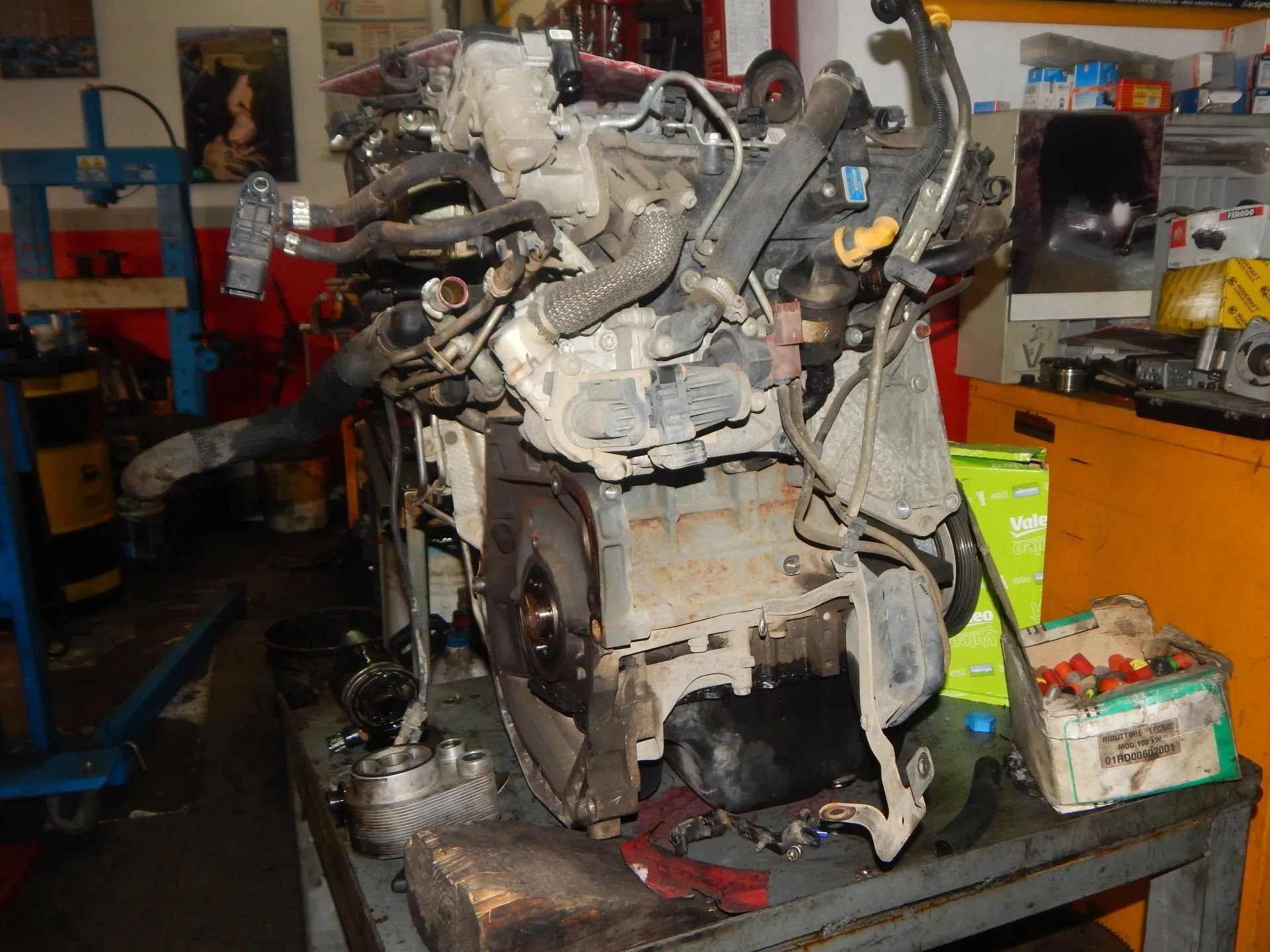 Large engine on a workshop floor with tools and equipment in the background