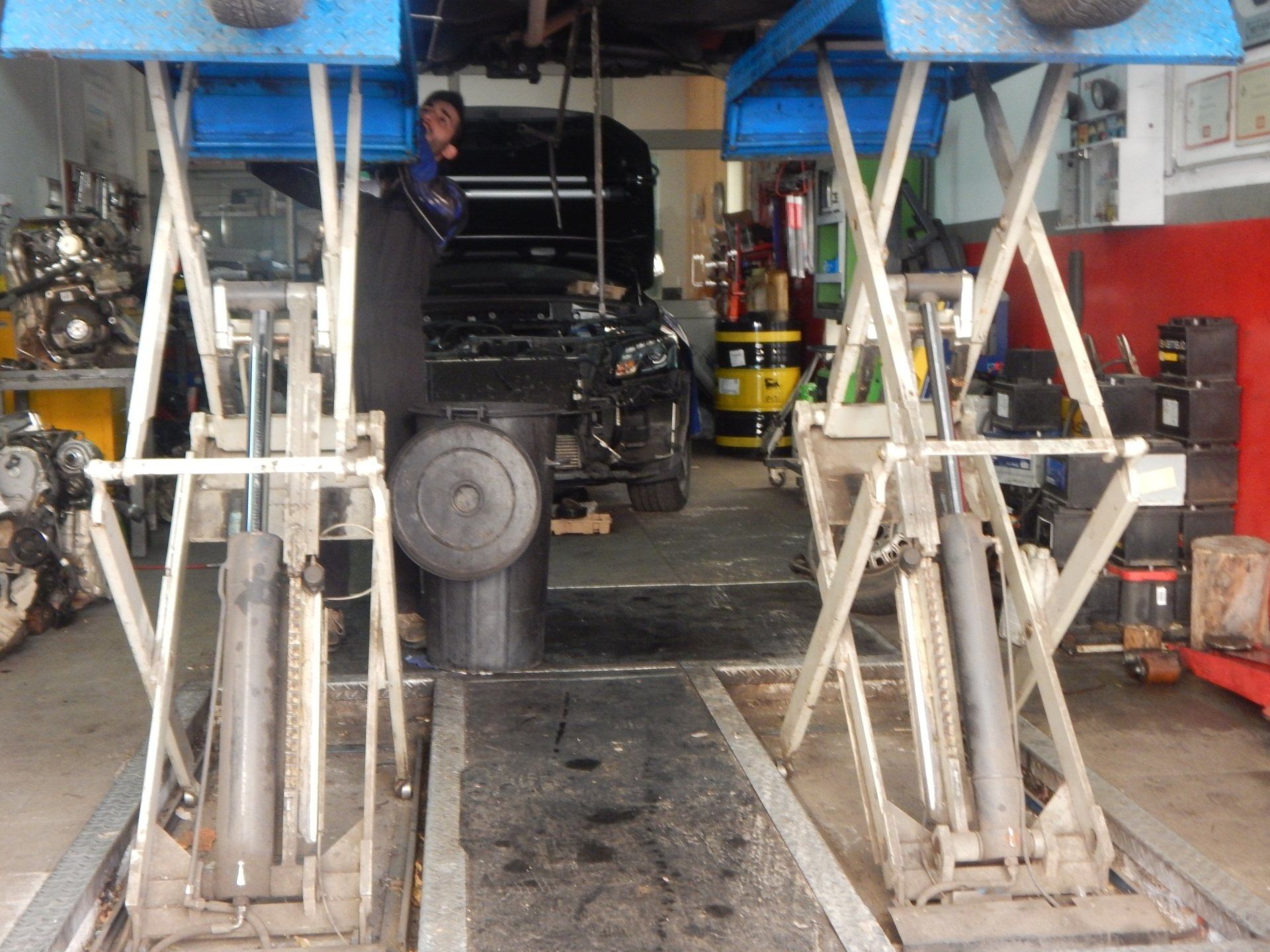 Truck parked between two blue hydraulic lifts in an auto repair shop