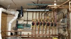 Plumbing system with copper pipes, pumps, and a boiler in a basement.